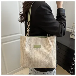 Dettaglio della trama intrecciata e del cinturino in pelle verde su borsa tote in paglia beige