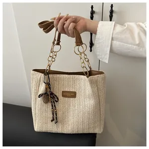 Dettaglio della borsa tote in paglia con tracolla in pelle e ciondolo con nappa