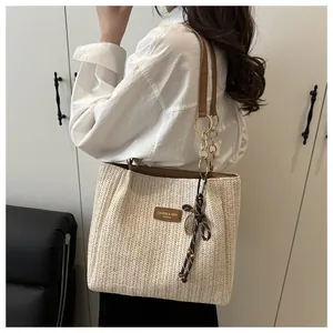 Dettaglio della borsa tote intrecciata con finiture in pelle marrone e catena dorata