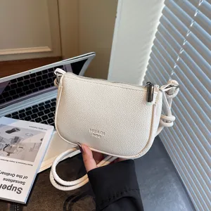 Minimalist white pebbled leather crossbody bag with knot strap and metallic HUAQI ROO logo