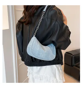 Detail of light blue glitter crescent bag with silver chain strap on model shoulder