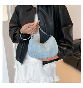 Detail of light blue glitter crescent bag with silver chain strap and shimmery texture