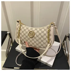 Detail of cream crossbody bag with brown monogram pattern and gold metal chain strap
