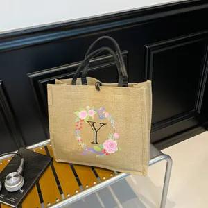 Detail der Jutetasche mit floralem Buchstaben Y Print und schwarzen Webgriffen