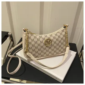 Detail of cream shoulder bag with M-letter print and golden circular metal hardware decoration