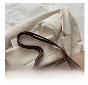 Close-up of wide leather handles and reinforced stitching on contrast color tote bag