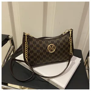 Detail of dark brown armpit bag with letter M print and gold metal logo on a chair