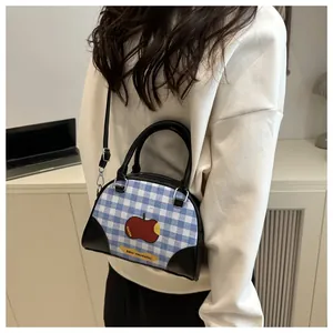 Detail of blue plaid boston bag with red apple print and black leather straps