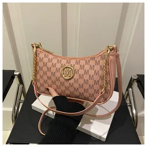Detail of pink monogrammed leather bag with gold M logo on decorative white books