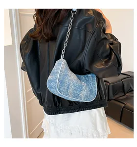 Detail view of light blue tweed texture bag with silver chain strap worn on shoulder