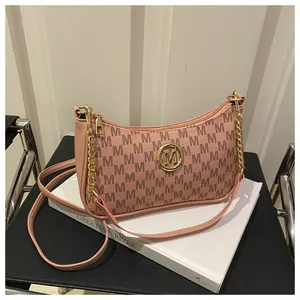 Detailed close-up of pink monogram underarm bag with gold M logo and chain accessory