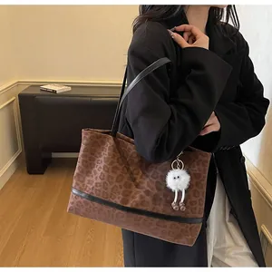 Dettaglio borsa tote leopardata con finiture in pelle nera e ciondolo di peluche
