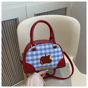 Detail of red and blue checkered square bag with apple print and stylish strap