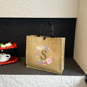 Detail der Jute-Tragetasche mit floralem S-Initial und schwarzen geflochtenen Seilgriffen
