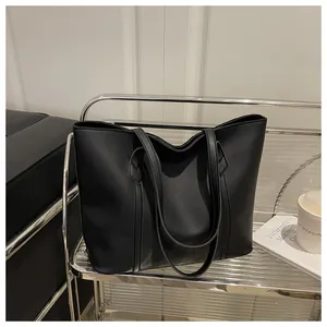 Detail shot of a black matte leather tote bag with long straps in a modern lifestyle setting