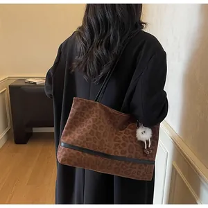 Dettaglio della borsa tote leopardata marrone con ciondolo peluche e tracolla nera