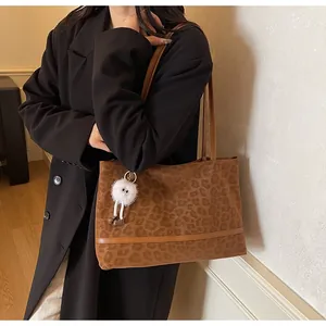 Dettaglio della borsa tote leopardata con base in pelle marrone e ciondolo di peluche