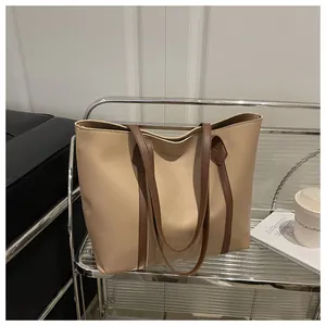 Detail of the chic beige and dark brown contrast tote bag on a modern glass shelf