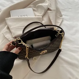 Brown leather underarm bag with M-pattern monogram, chain strap, and crossbody strap