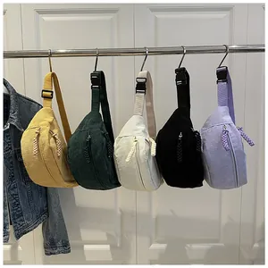 Detail view of colorful corduroy waist bags in yellow, green, and cream on a hanger