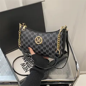 Chic black monogram underarm bag with golden M-logo and adjustable shoulder strap