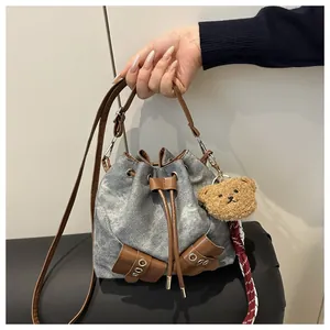 Close-up of drawstring bucket bag with washed denim fabric and brown leather straps