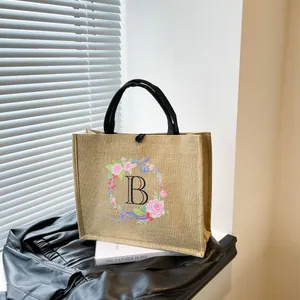 Detail der Jute-Tragetasche mit rosa Blumen-Buchstabe B und schwarzem Knopfverschluss