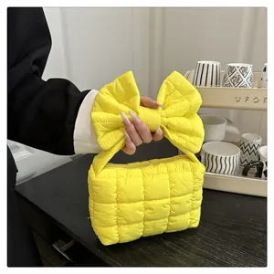 Dettaglio della trama trapuntata e del manico a fiocco giallo della borsa a mano