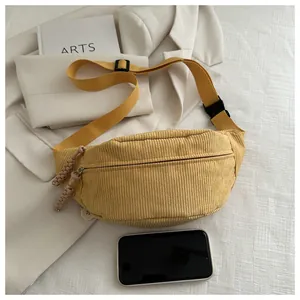 Detail of yellow corduroy belt bag showing texture, dual zippers and strap buckle