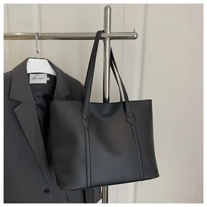 Detailed view of matte black tote bag with vertical stitching and smooth leather texture