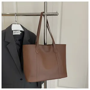 Close-up of textured brown leather tote bag with vertical stitching for office commute