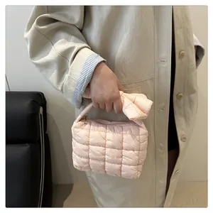 Detail of light pink quilted puffer handbag with soft bow handles and zipper closure
