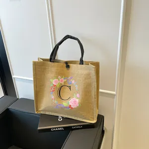 Detailansicht der Leinentasche mit Blumenkranz-C-Motiv und schwarzem Knopfverschluss