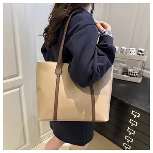 Detailed view of a minimalist contrast-stitch tote bag worn by a model in a home setting