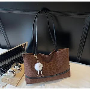 Dettaglio della borsa tote leopardata con ciondolo di peluche e scena da scrivania
