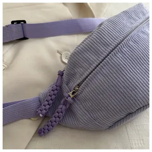Close-up of purple corduroy chest bag featuring textured fabric and woven zipper pull