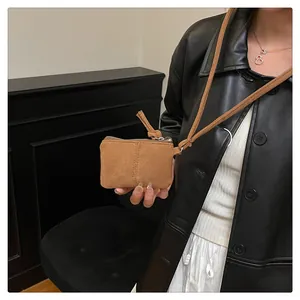 Detailansicht der braunen Mini-Tasche aus Wildleder mit silbernem Reißverschluss und Gurt