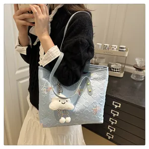 Detail of light blue tote bag featuring butterfly embroidery and plush cloud charm