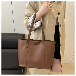 Dark brown leather tote bag styled with a beige trench coat for a stylish commuter look