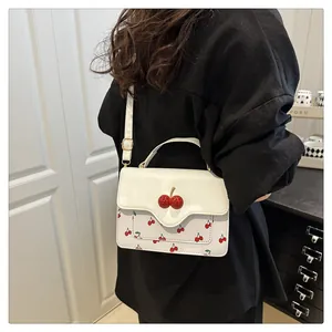 Detail of white cherry print crossbody bag with 3D cherry buckle shown on a model
