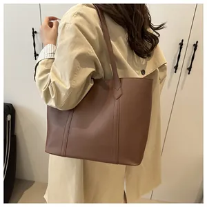Close-up of brown matte leather tote bag with vertical stitching and slim shoulder strap