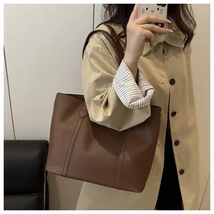 Deep brown leather tote bag with vertical stitching and wide shoulder strap detail