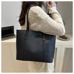 Detail showing matte black leather tote bag capacity and reinforced triangular strap stitching