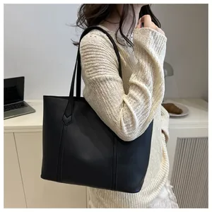 Detail view of large black leather tote bag showing vertical stitching and reinforced handle
