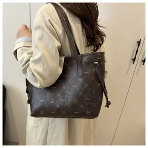 Détail d'un sac cabas en cuir marron à motifs, porté à l'épaule par un mannequin en manteau