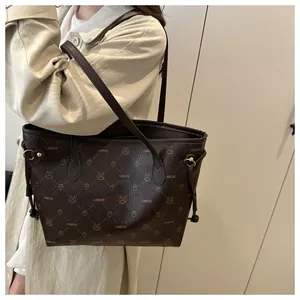 Détail d'un sac cabas marron foncé avec motif logo et imprimé lapin porté à l'épaule