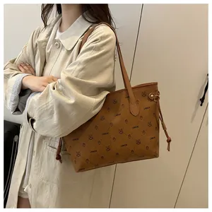 Vue détaillée du sac cabas marron à motif logo et glands décoratifs latéraux