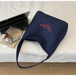 Detail of navy blue canvas tote bag with red 'C'est la vie' embroidery for daily use