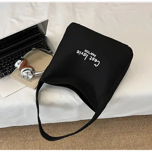 Flat lay of black canvas tote bag with C'est la vie print next to a laptop and books
