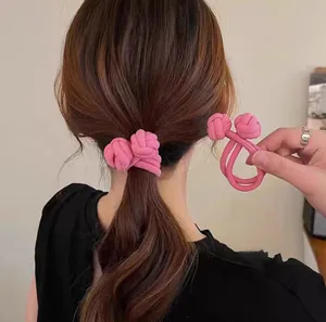 Roze geknoopte elastische haarelastiek met ribbeltextuur op een paardenstaart en in hand